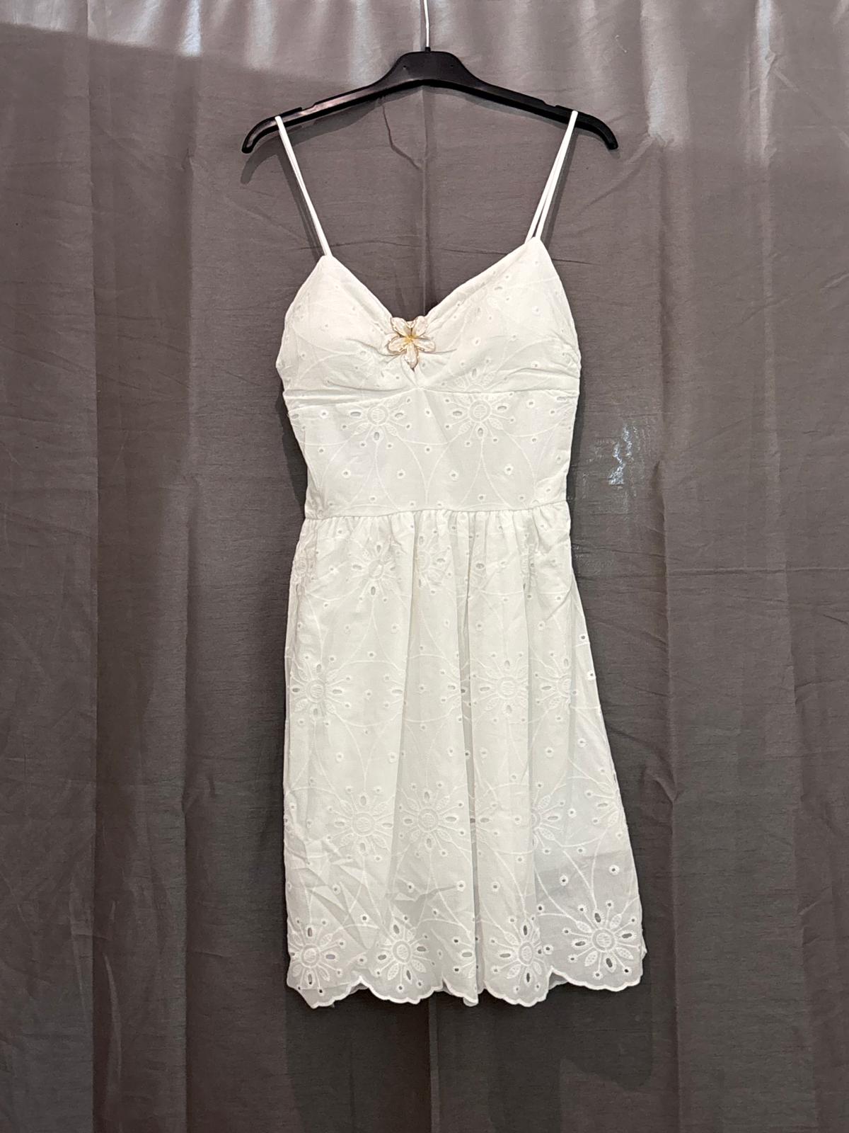 Robe courte blanche en broderie anglaise, bretelles fines et bijou fleur
