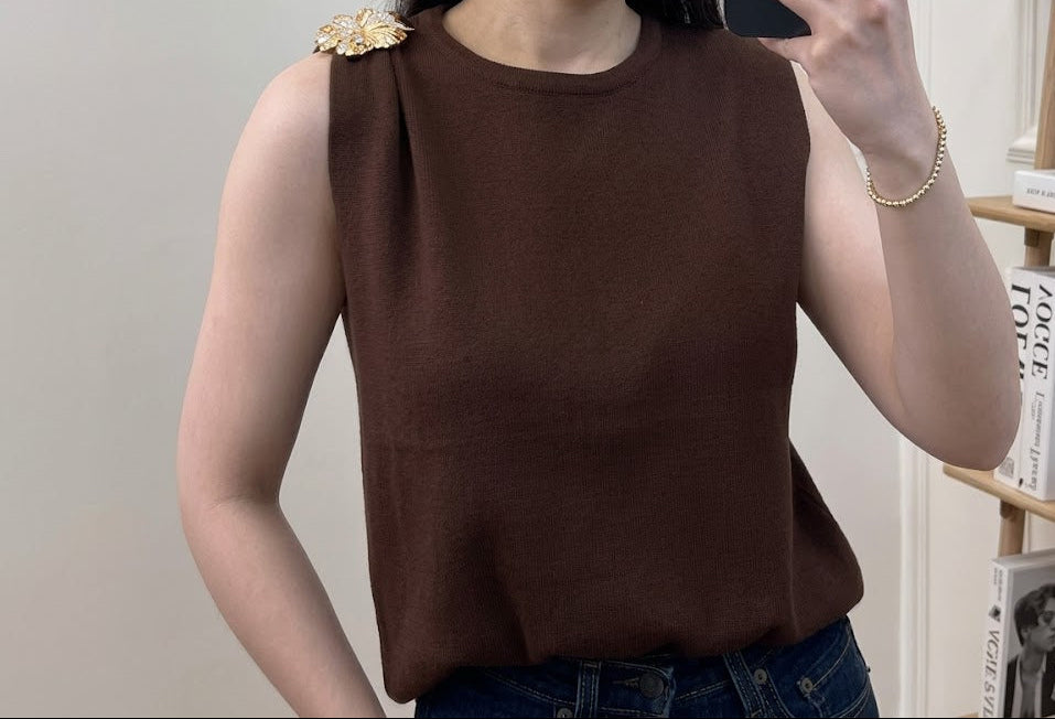 Top en maille fine col rond sans manches avec broche florale dorée sur l'épaule