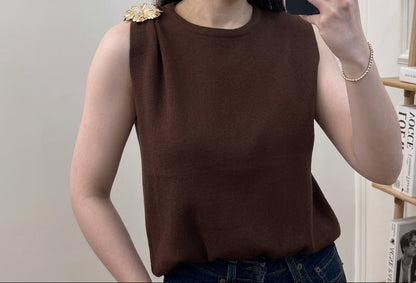 Top en maille fine col rond sans manches avec broche florale dorée sur l'épaule