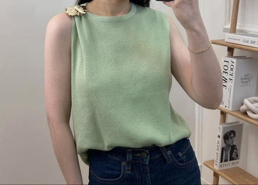 Top en maille fine col rond sans manches avec broche florale dorée sur l'épaule