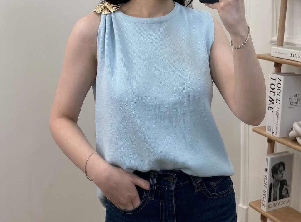 Top en maille fine col rond sans manches avec broche florale dorée sur l'épaule