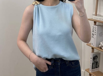 Top en maille fine col rond sans manches avec broche florale dorée sur l'épaule