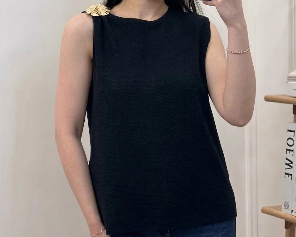 Top en maille fine col rond sans manches avec broche florale dorée sur l'épaule